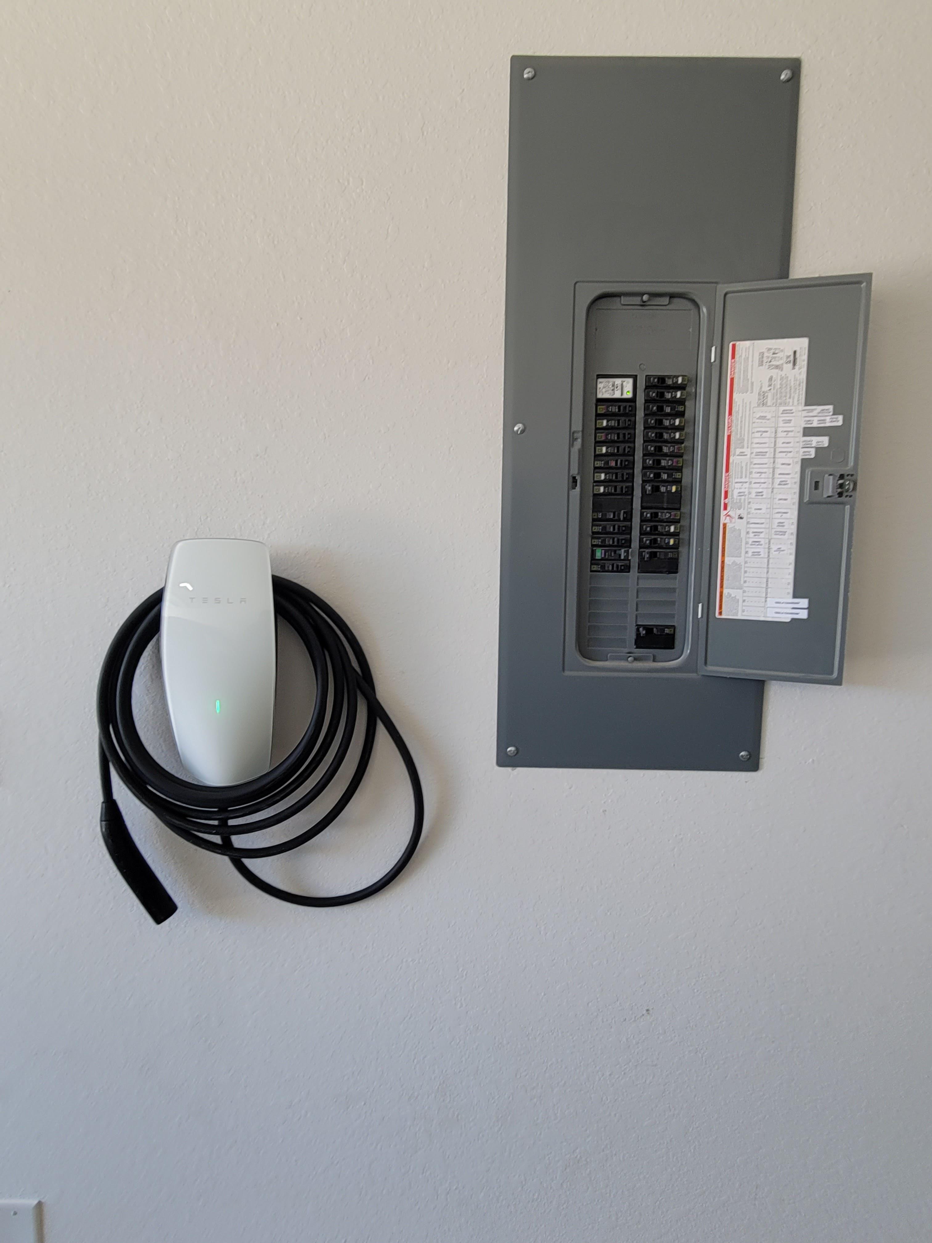 Tesla wall charger installation beside an electrical panel